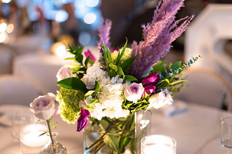 Centerpiece of roses, hydrangea and lilac pampas beside floating candles