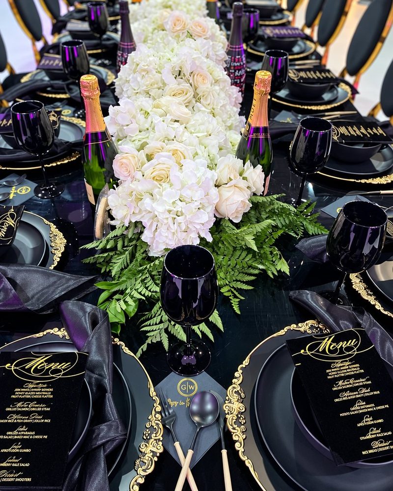 Black and gold dinner table with a white rose and hydrangea runner