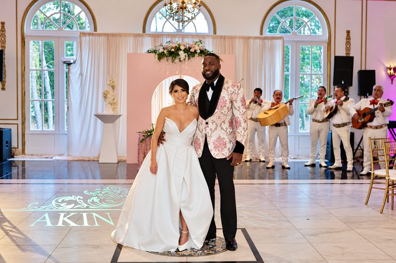 Bride and groom on a monogrammed dance floor with a mariachi band behind them